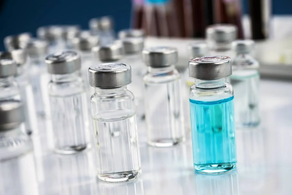 Vials of clear and blue liquid in a laboratory setting, representing research applications of Semax peptide and its role in biochemical studies.